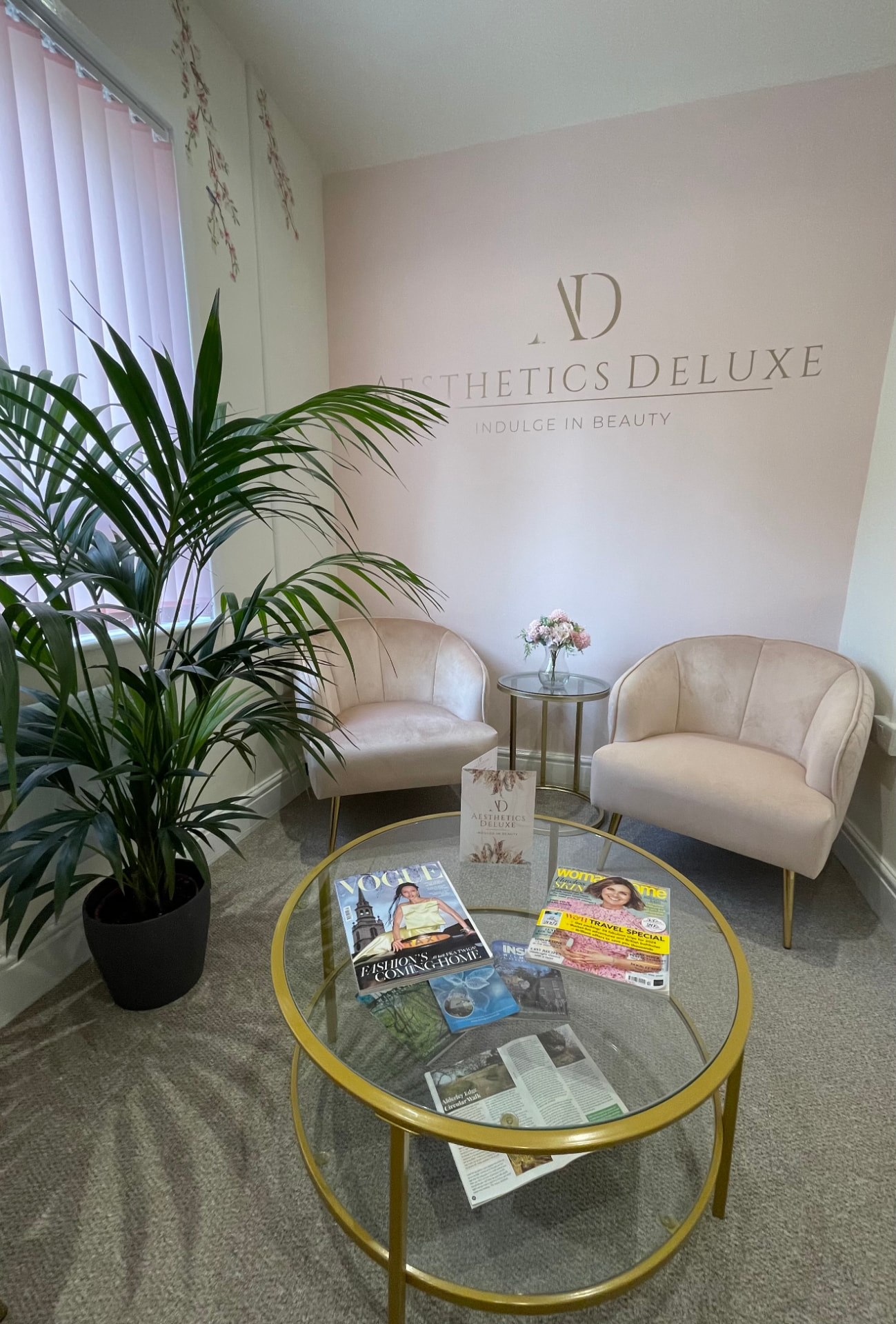 Aesthetics Deluxe reception area in Wilmslow with blush pink walls, gold signage and velvet chairs